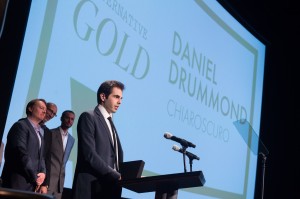Daniel Drummond recebendo o prêmio e atrás Roy Conli, Don Hall e Chris Williams (time vencedor do Oscar por Operação Big Hero 6)