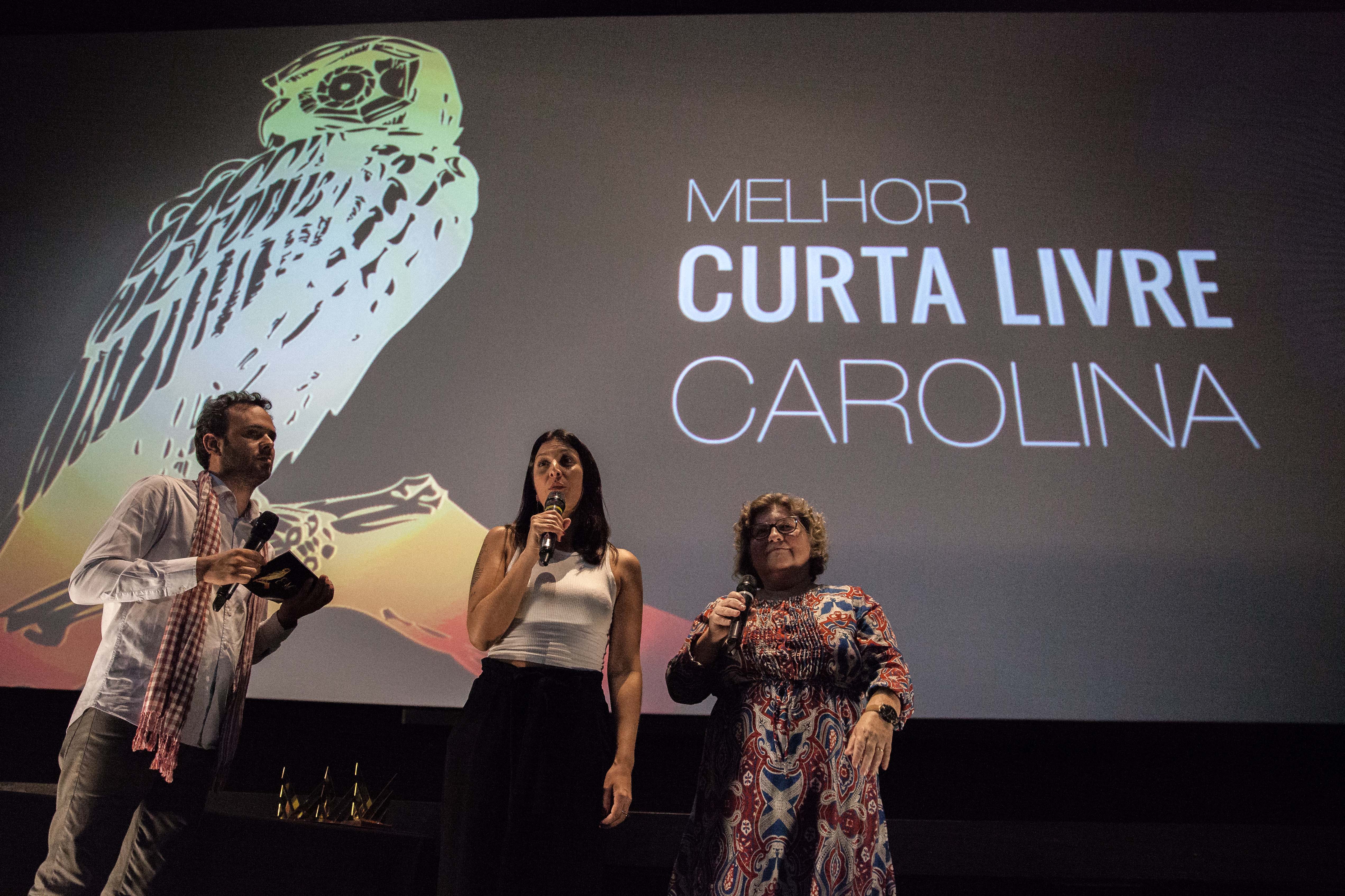 A professora Teresinha Cipolotti, e os coordenadores Martin Eikmeier e Juliana Salazar entregando o prêmio para o documentário Carolina